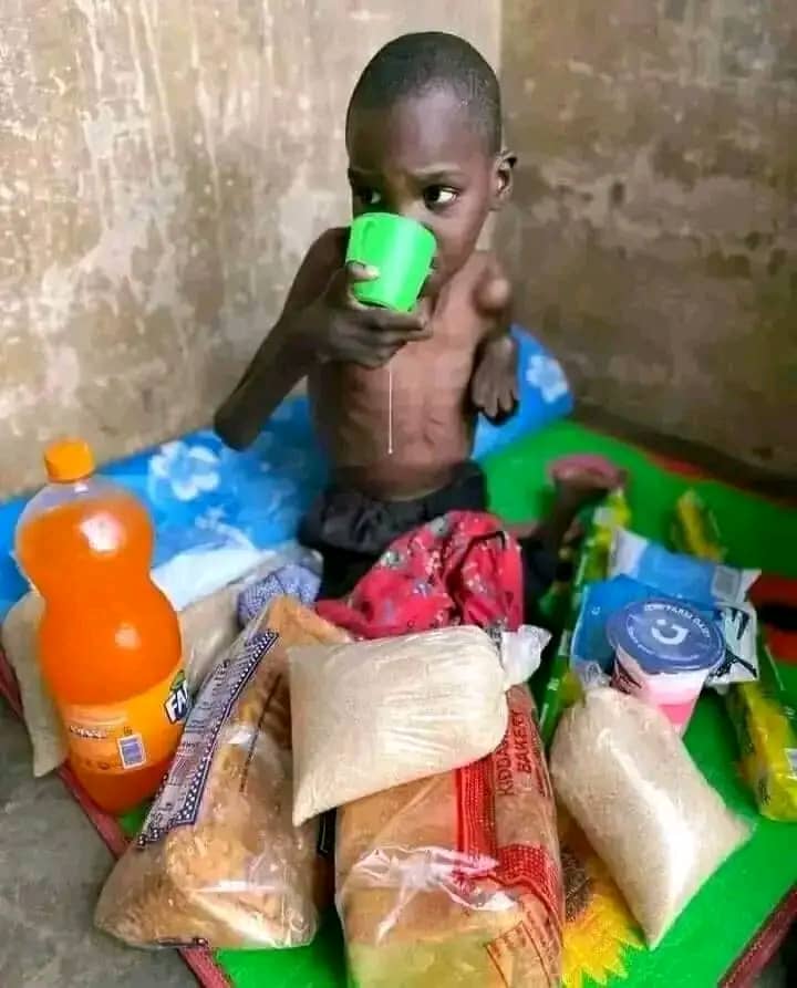 Projects 2 Young child drinking from a cup beside donated food and supplies
