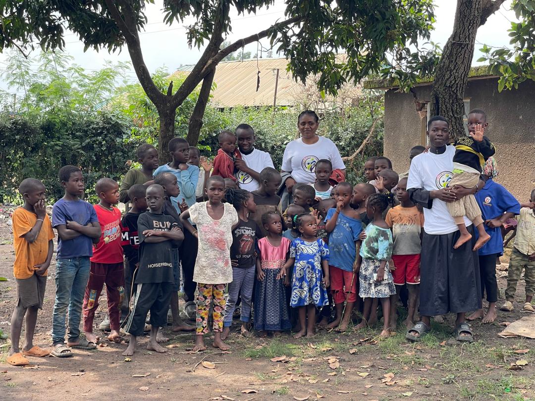 Large group of children and adults gathered under trees for a group photo