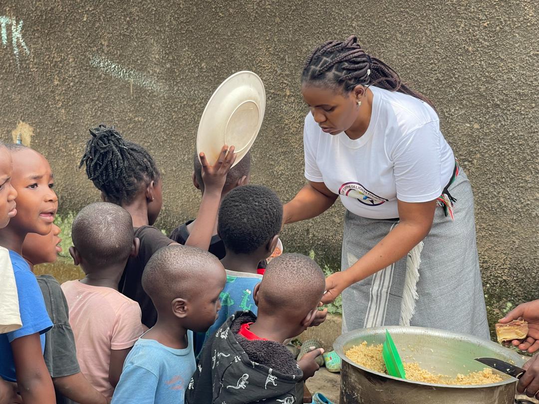 Children holding out plates as a volunteer serves a hot meal